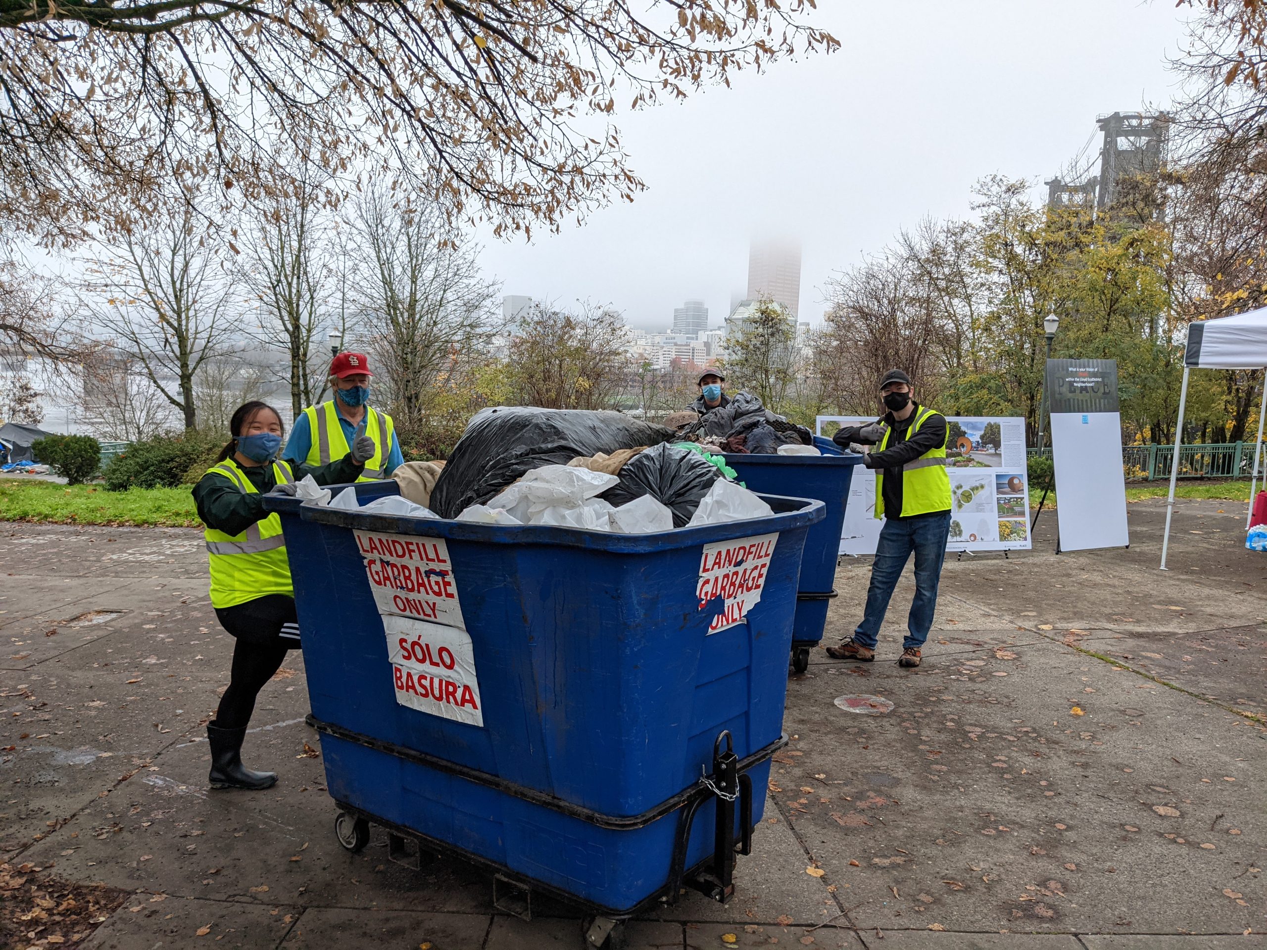 Image of staff and volunteers wheeling the trash bins