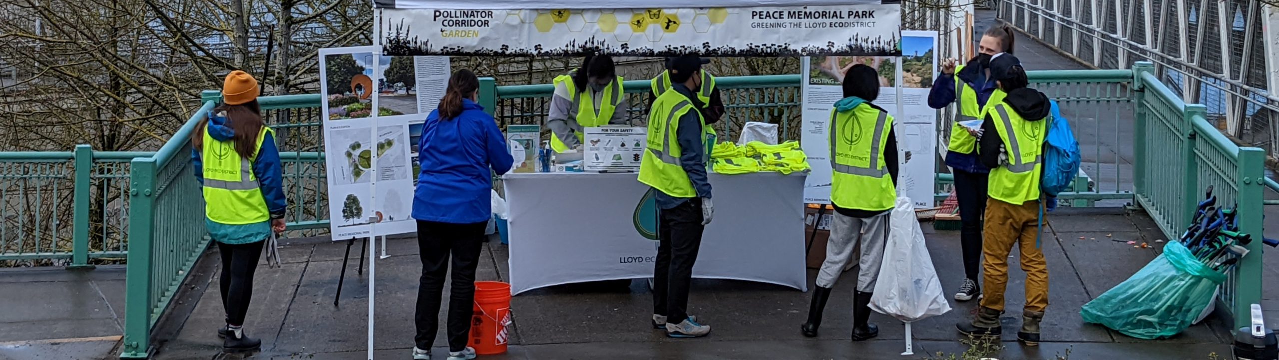 a group of volunteers wearing green safety vest check in at a table outside