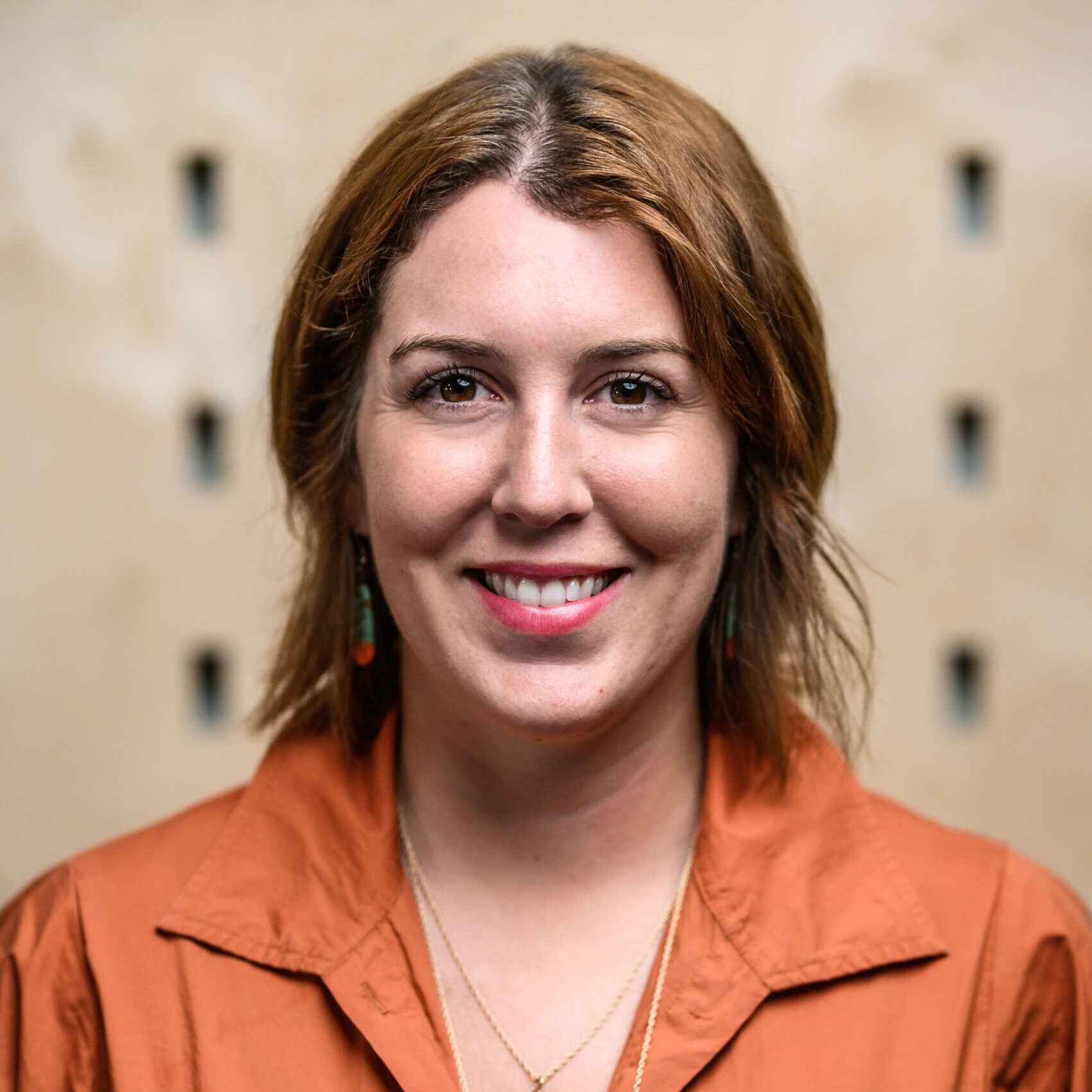 Image of Kristin Leiber. Photo is a headshot of a women with brown hair and orange shirt, looking directly at the camera smiling.