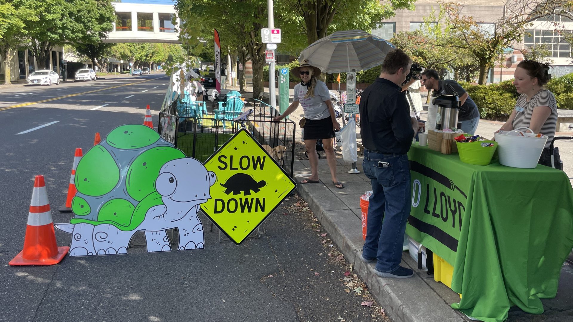a photo from the 2023 Park(ing) Day featuring green turf grass laid out in the street and fence creating a temporary dog park.