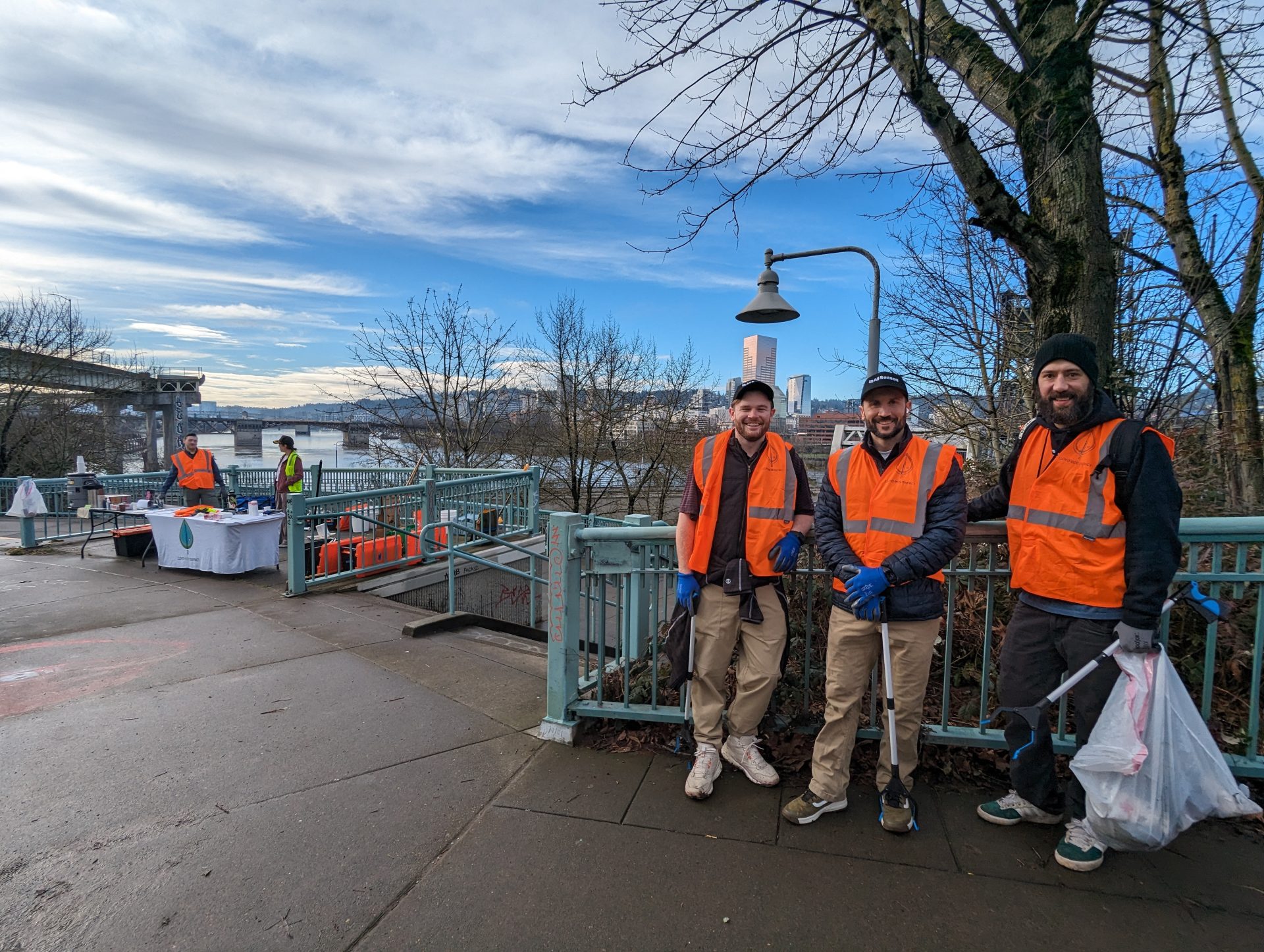 Three people posing in front of a fence at Peace Memorial Park, showing the progress of their cleanup