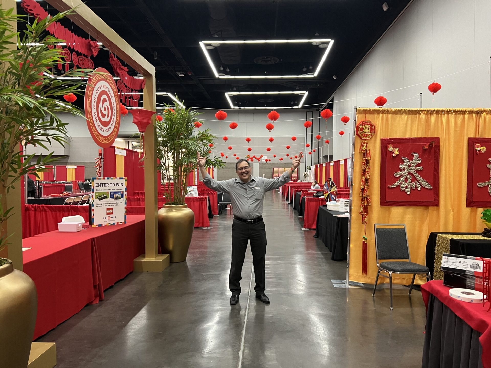 Man standing between event kiosks, raising his hands