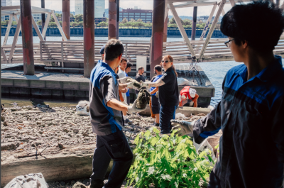 A few people on the riverbank assisting with cleaning up the beach