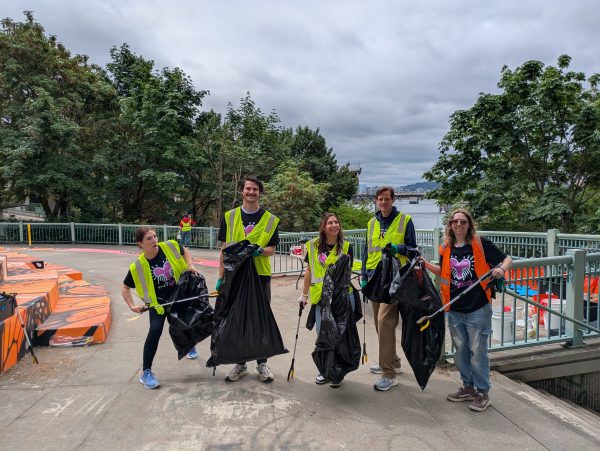 Five volunteers in vest and holding garbage bags pose for a photo at Peace Memorial Park