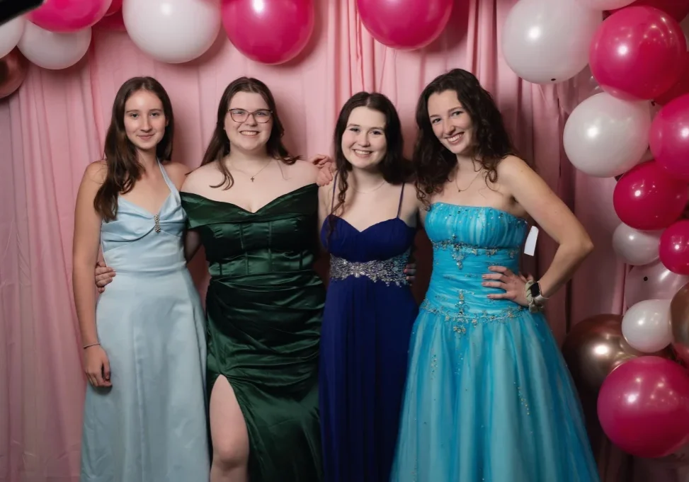 Four women in prom dresses posing for a photo
