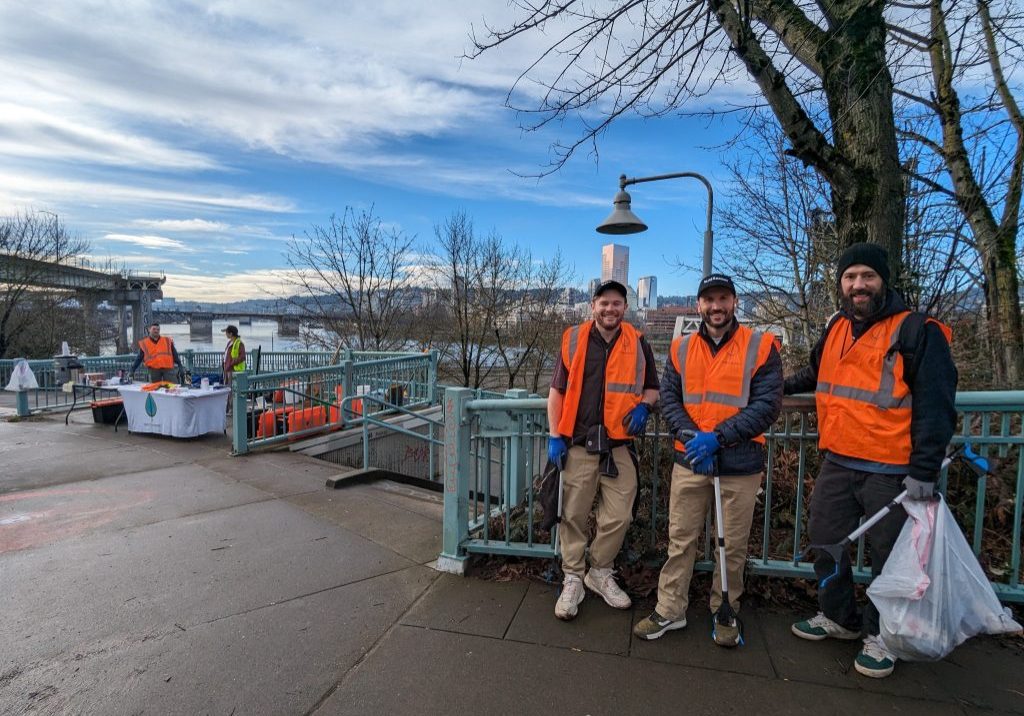 Three people posing in front of a fence at Peace Memorial Park, showing the progress of their cleanup
