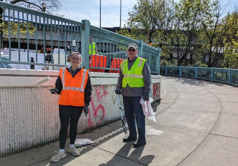 Two people posing in front of a fence at Peace Memorial Park, showing their cleanup progress.