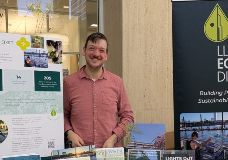 image of joshua standing behind a a table with Lloyd ExoDistrict info and signage