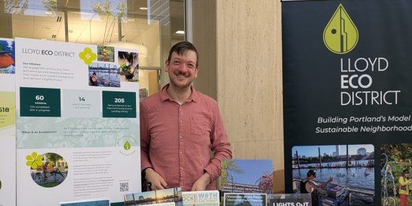 image of joshua standing behind a a table with Lloyd ExoDistrict info and signage