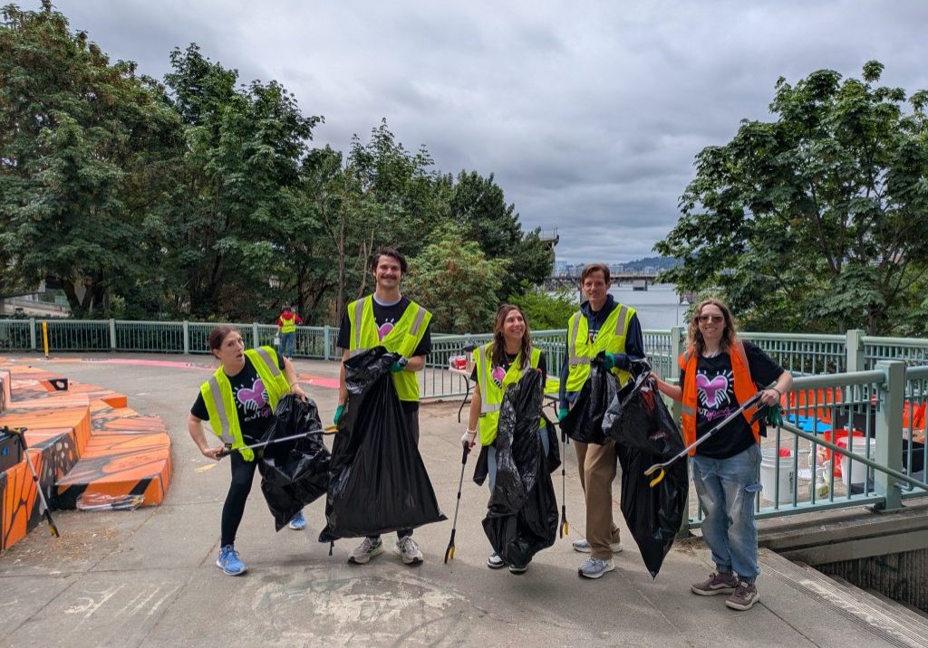 Five volunteers in vest and holding garbage bags pose for a photo at Peace Memorial Park