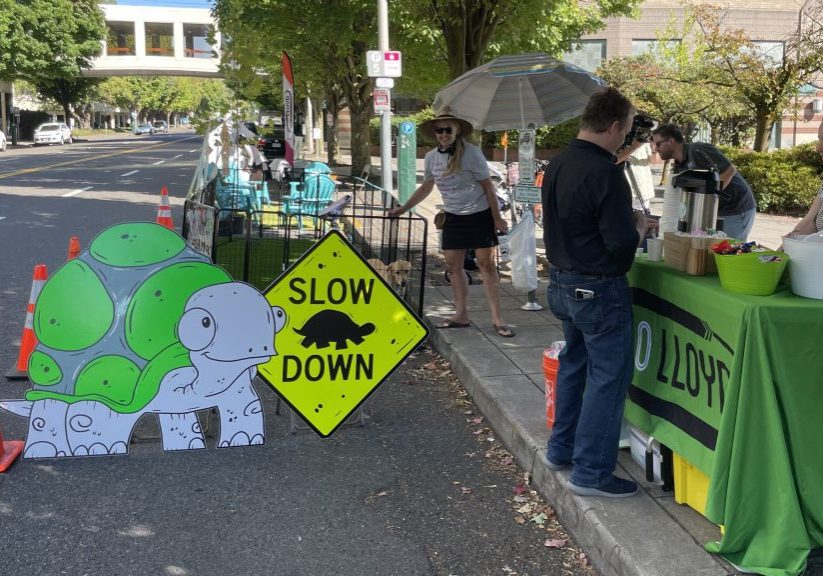 a photo from the 2023 Park(ing) Day featuring green turf grass laid out in the street and fence creating a temporary dog park.