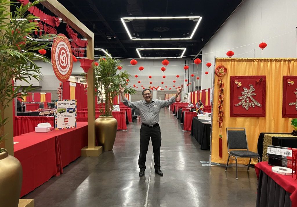 Man standing between event kiosks, raising his hands