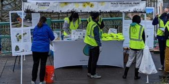a group of volunteers wearing green safety vest check in at a table outside